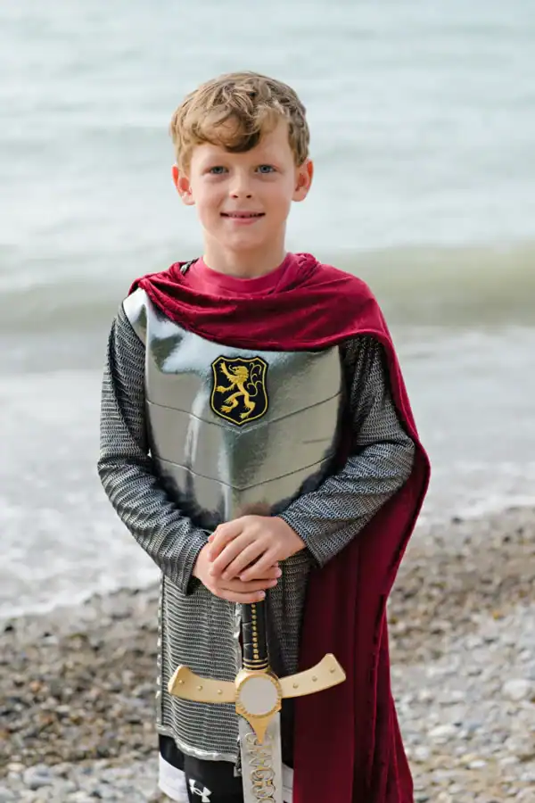 Child dressed as knight by the sea
