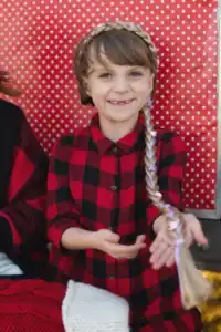 Child smiling in red plaid shirt, braided hair