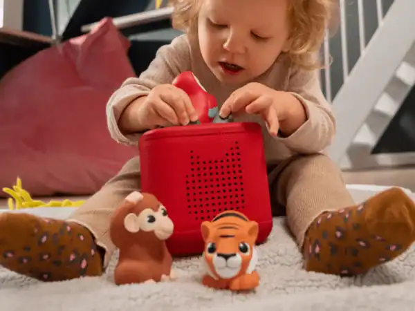 Child playing with red toy speaker and figurines.