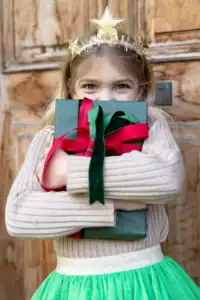 Girl hugging wrapped gift with a star headband