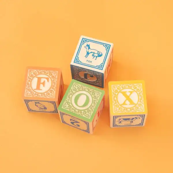 Colorful alphabet blocks spell 'FOX' on orange background.