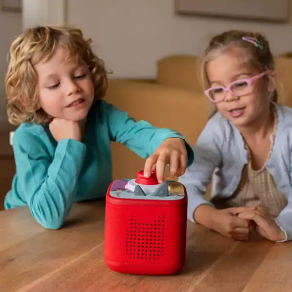 Children playing with red audio box on table.