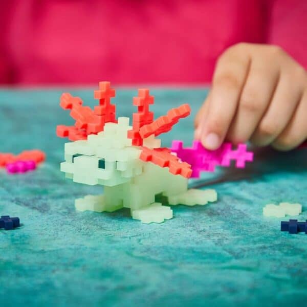Child builds axolotl with colorful building blocks.