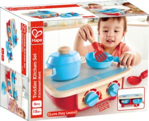 Toddler playing with toy kitchen cooking set