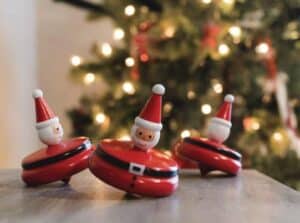 Three Santa spinning tops by Christmas tree
