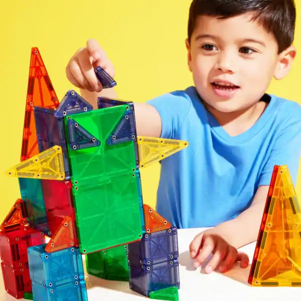 Child building with colorful magnetic tiles.