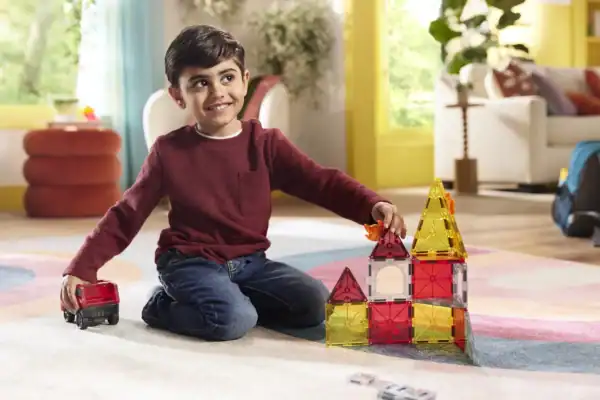 Child playing with colorful magnetic blocks on floor.