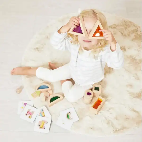 Child playing with wooden triangle toys on rug.