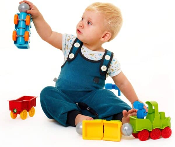 Child playing with colorful toy train set.