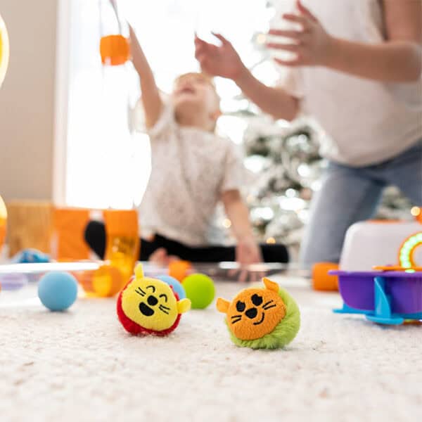 Children playing with colorful cat toys indoors.