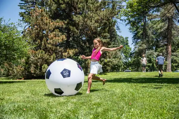 Child playing with giant soccer ball in park.