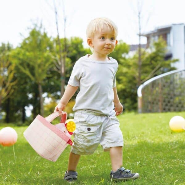 Child walking on grass with a basket.