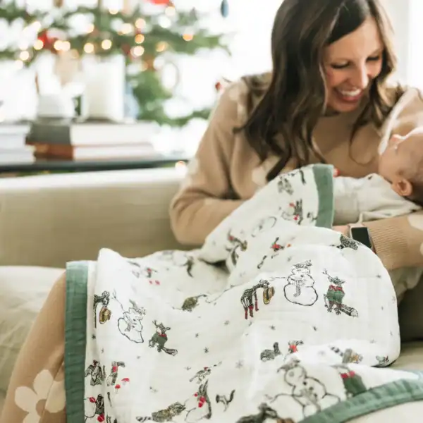Woman smiling holding baby in Christmas scene.