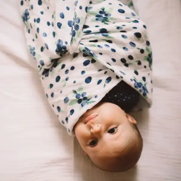 Baby wrapped in floral patterned blanket.