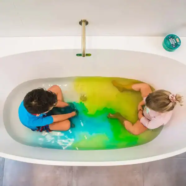 Children in colorful bathwater, playing in tub.