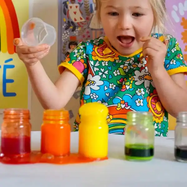 Child excited with colorful paint jars.