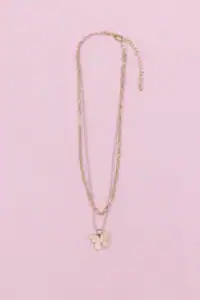 Gold butterfly pendant necklace on pink background.