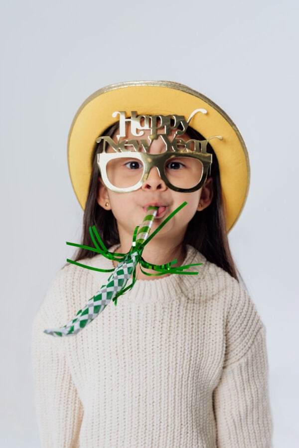 Child celebrating New Year with hat and blower