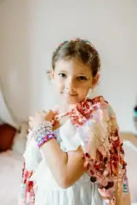 Child wearing colorful sequined dress, smiling confidently.