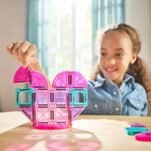 Child building with colorful magnetic tiles.
