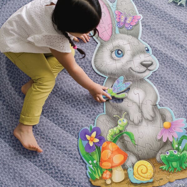 Child assembling bunny puzzle on blue carpet.
