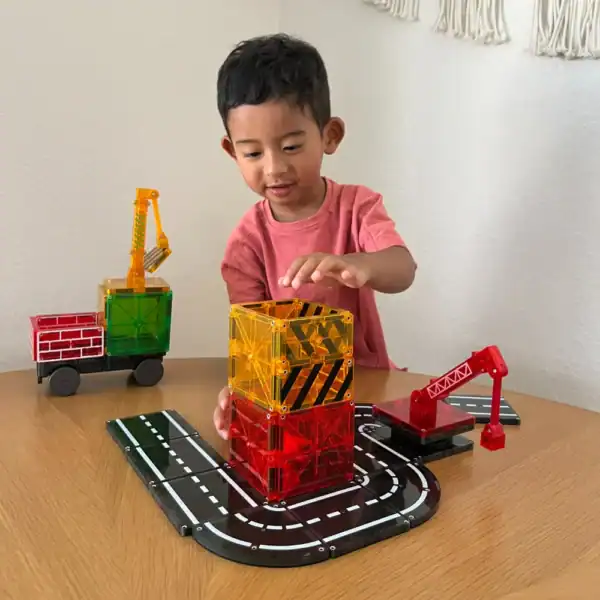 Child building with colorful toy blocks and roads.