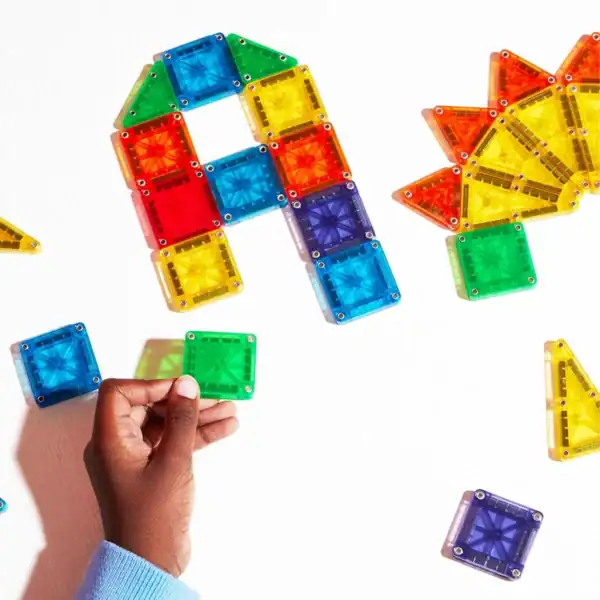 Child assembling colorful magnetic tiles.