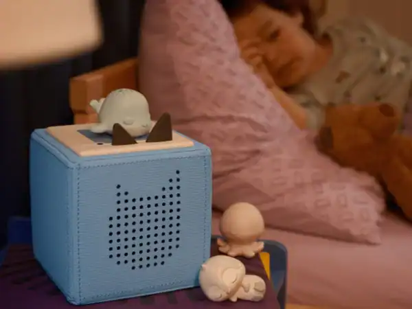 Child sleeping with audio device and toy figures