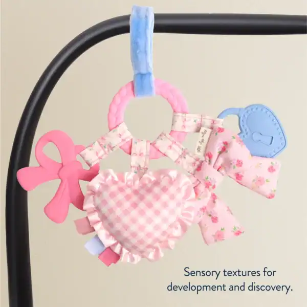 Baby toy with heart and bow, sensory textures.