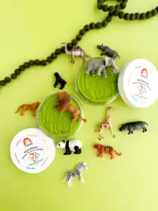 Toy animals with play dough on green background