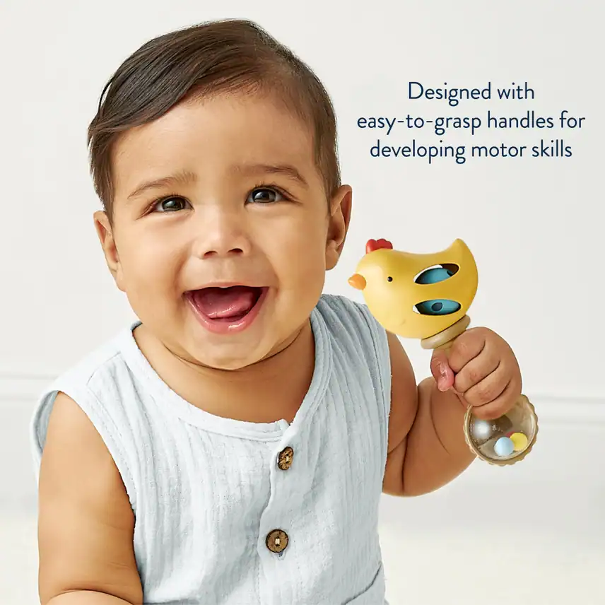 Baby holding toy with chicken design for motor skills.