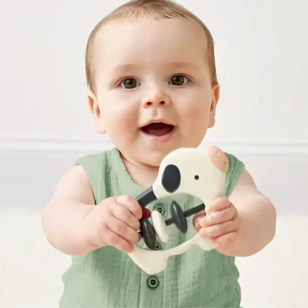 Baby holding a cow-shaped rattle toy.