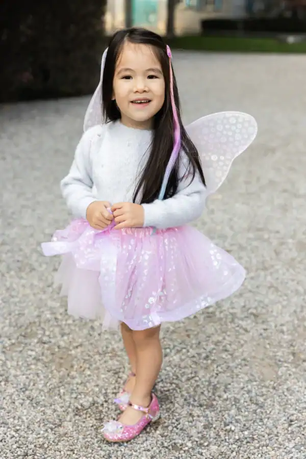 Smiling child in pink fairy costume outdoors